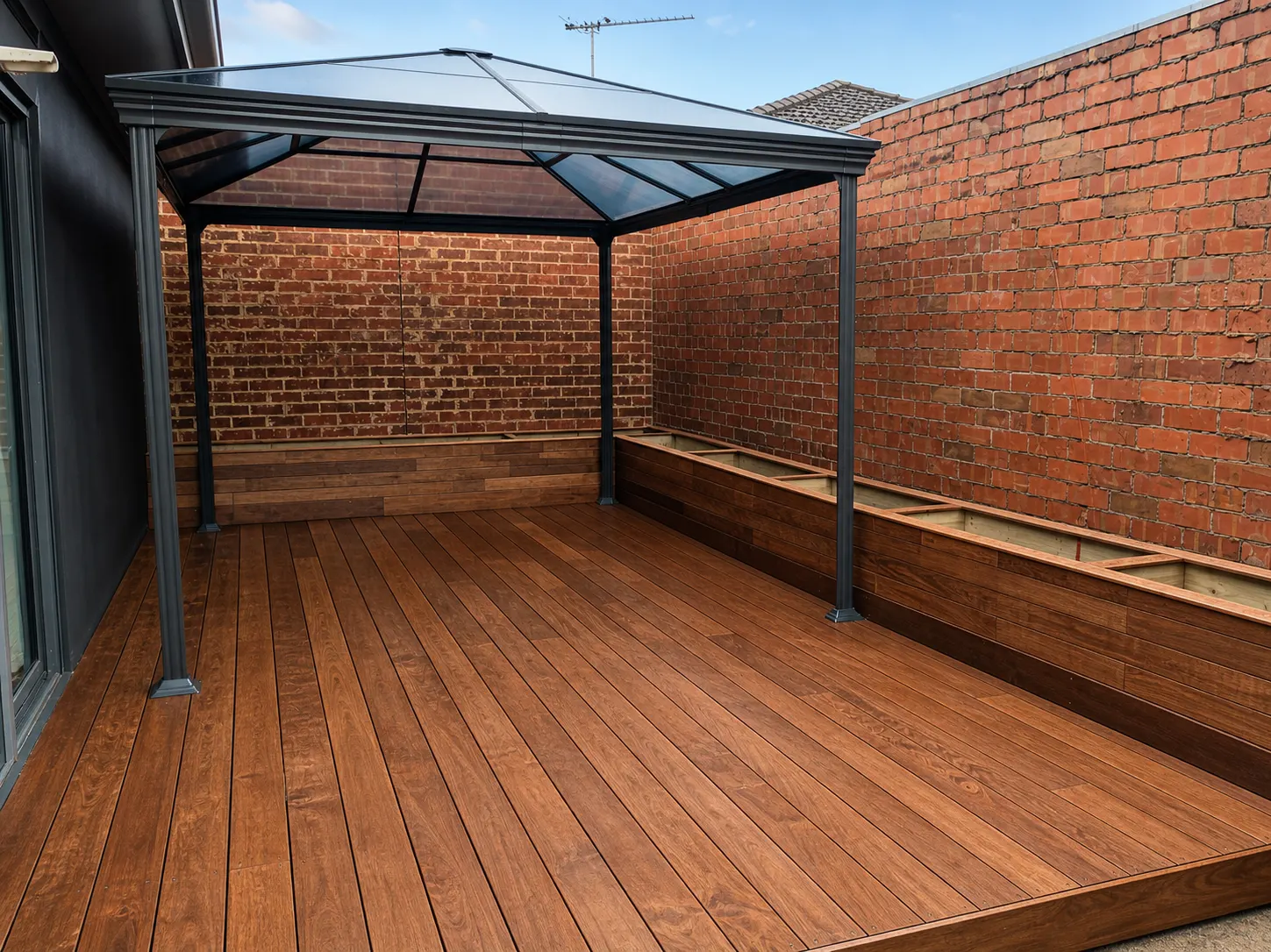Finished timber courtyard deck with raised planters and a dark framed gazebo